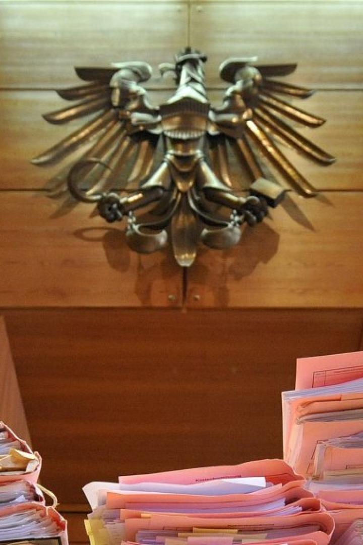 Ein Stapel Akten vor einem hölzernen Hintergrund mit einem Adlerwappen.