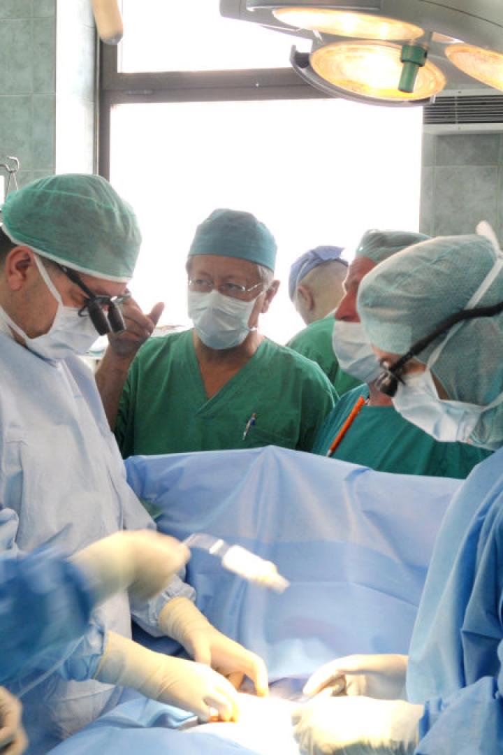 Ein Operationsteam führt eine Operation in einem hell erleuchteten Operationssaal durch.