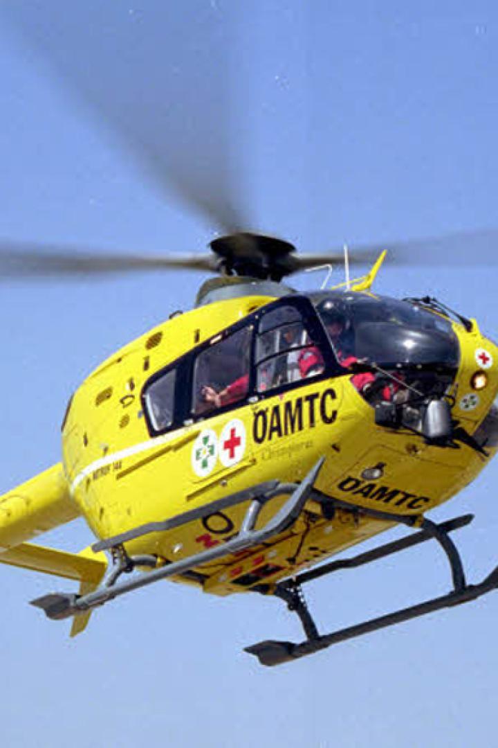 Ein gelber ÖAMTC Hubschrauber fliegt über einem wolkenlosen Himmel.