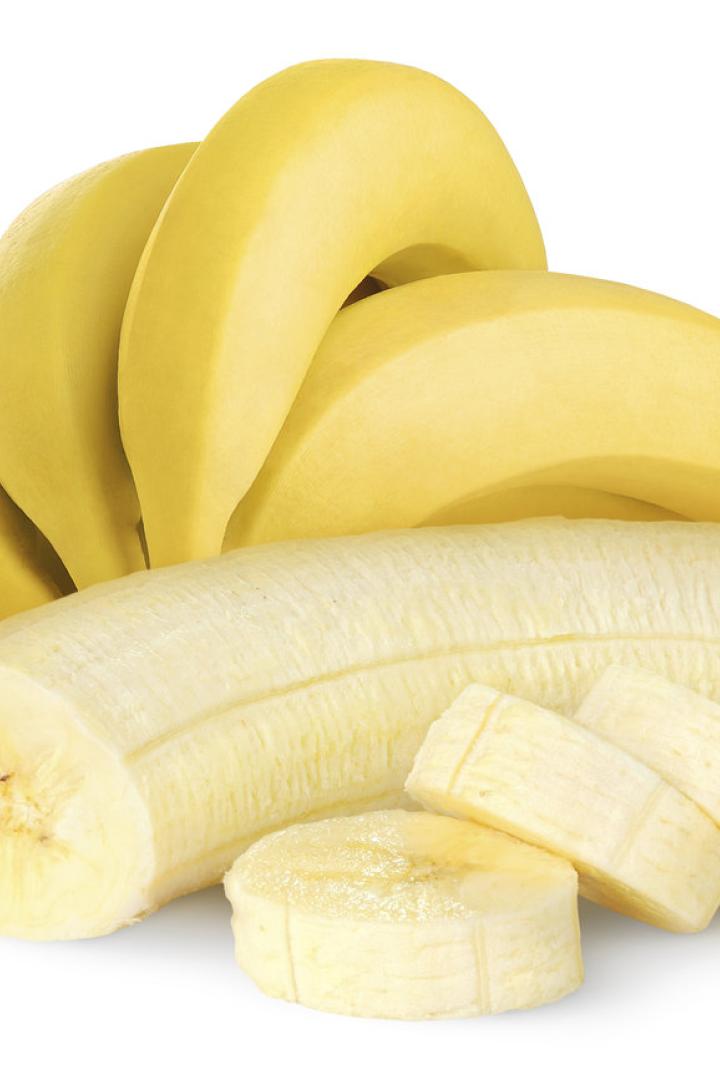 Eine geschälte, aufgeschnittene Banane vor einem Bündel gelber Bananen