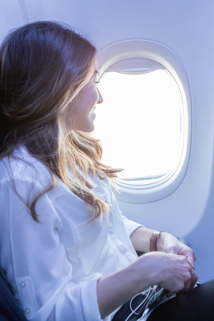 Junge Frau sitzt im Flieger.