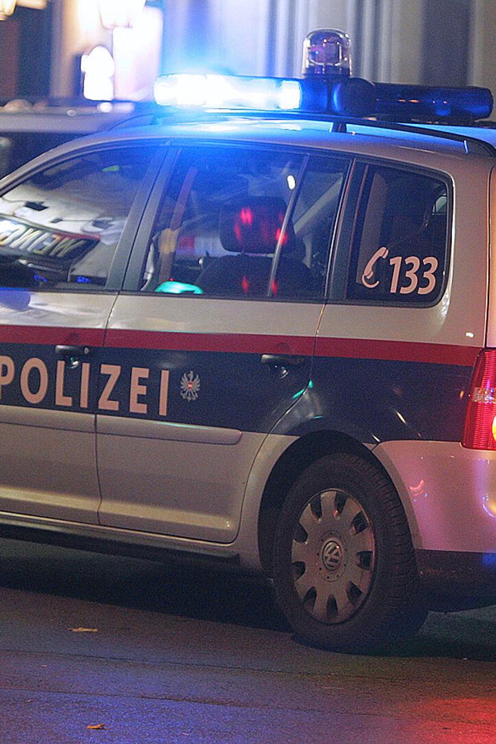 Ein silbernes Polizeiauto mit Blaulicht steht auf der Straße.