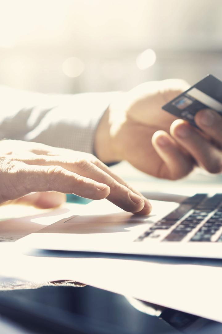 Ein Geschäftsmann arbeitet mit einem Laptop und hält eine Kreditkarte in der Hand. Online-Zahlungen werden getätigt.