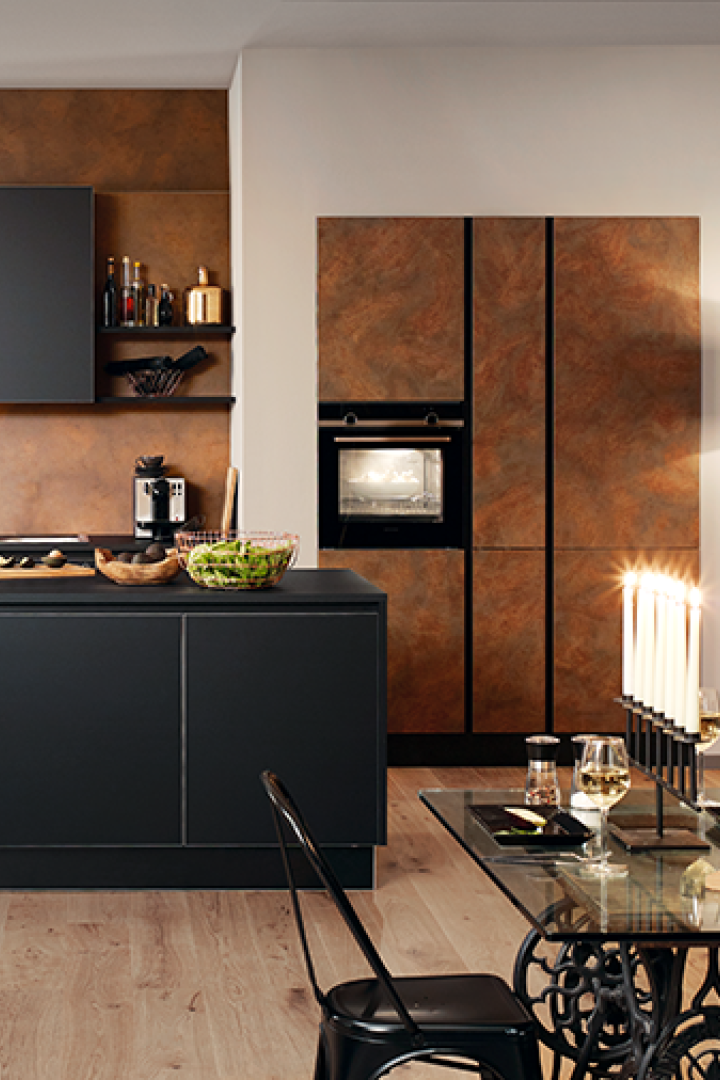 Moderne Küche mit dunklen Schränken, Kochinsel, Esstisch mit Brot und Kerzen sowie dekorativen Elementen an den Wänden.