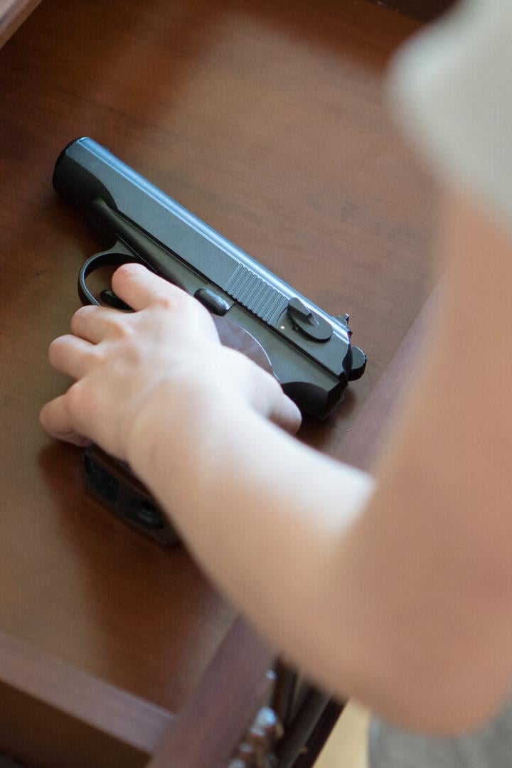 Eine Kinderhand greift nach einer Pistole, die in einer Lade liegt.