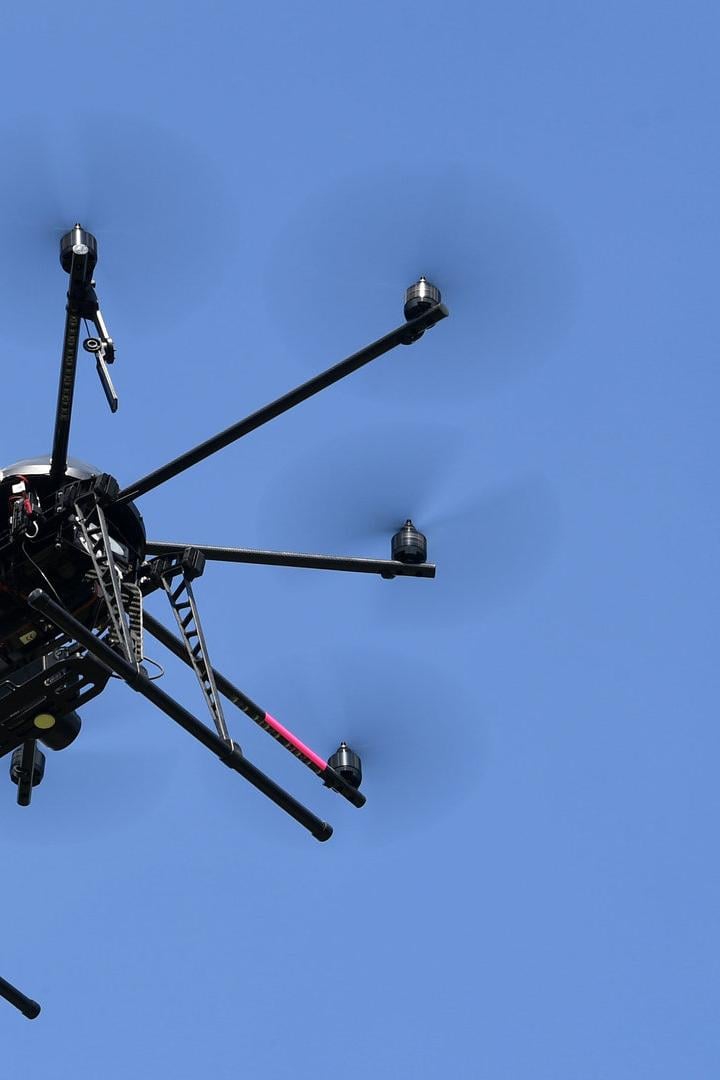 Zwei Drohnen fliegen vor blauem Himmel.