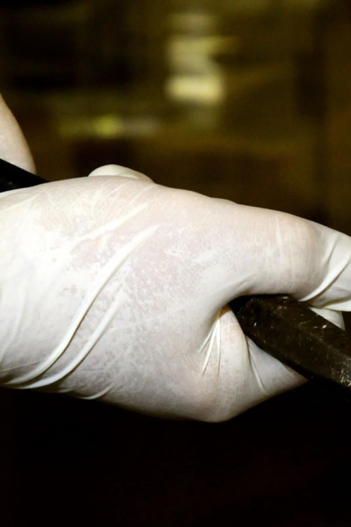 Eine Person mit Handschuhen bricht mit einem Brecheisen eine Tür auf.