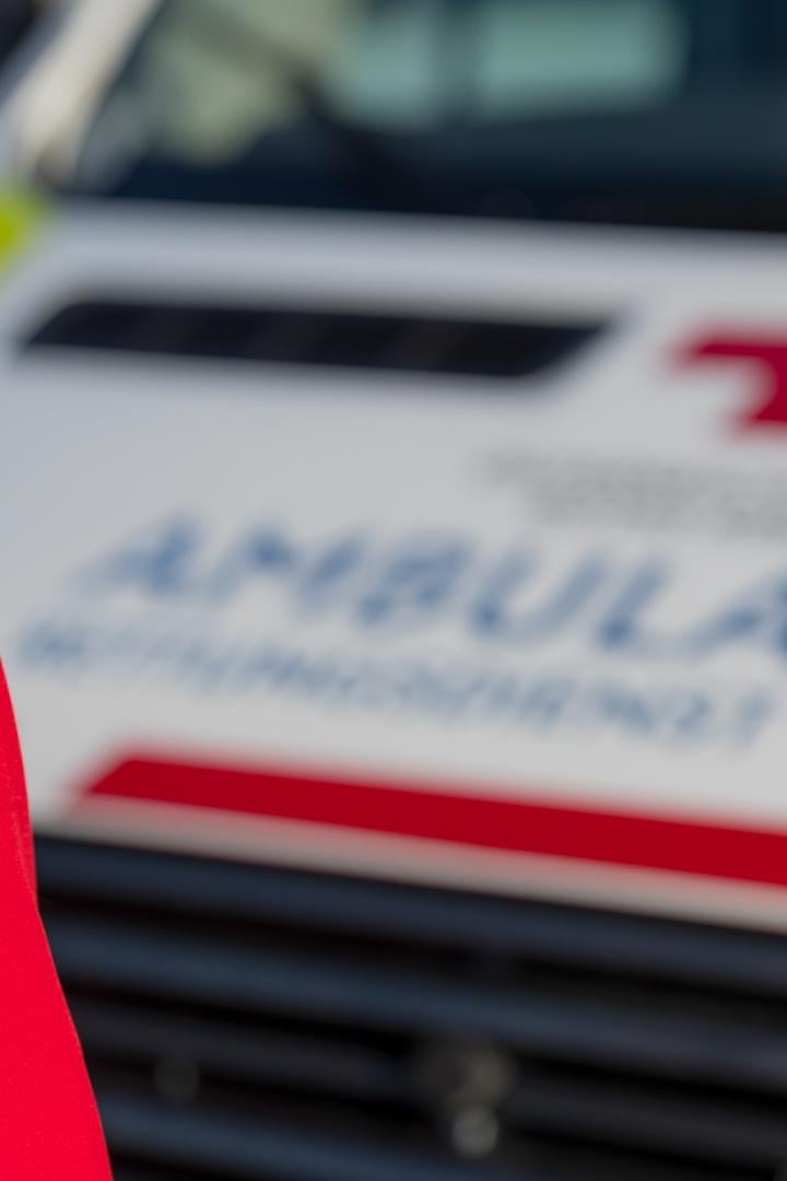 Eine Person in Rettungsjacke steht mit dem Rücken zur Kamera, im Hintergrund ist ein Rettungswagen zu sehen.