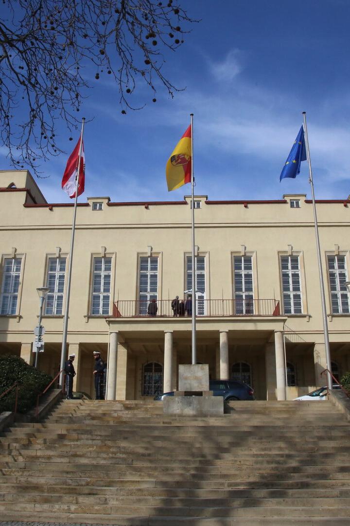 Vor einem Gebäude wehen die Flaggen von Österreich, Spanien und der EU.