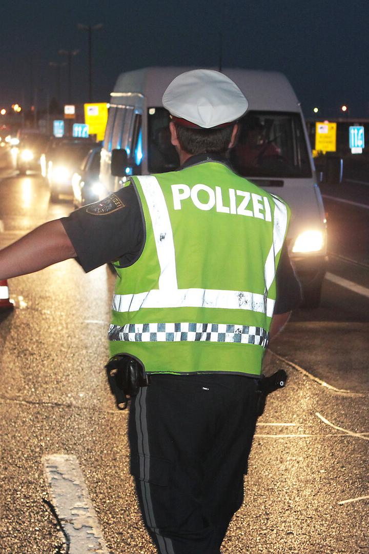 Ein Polizist leitet den Verkehr bei einer nächtlichen Kontrolle auf der Autobahn.
