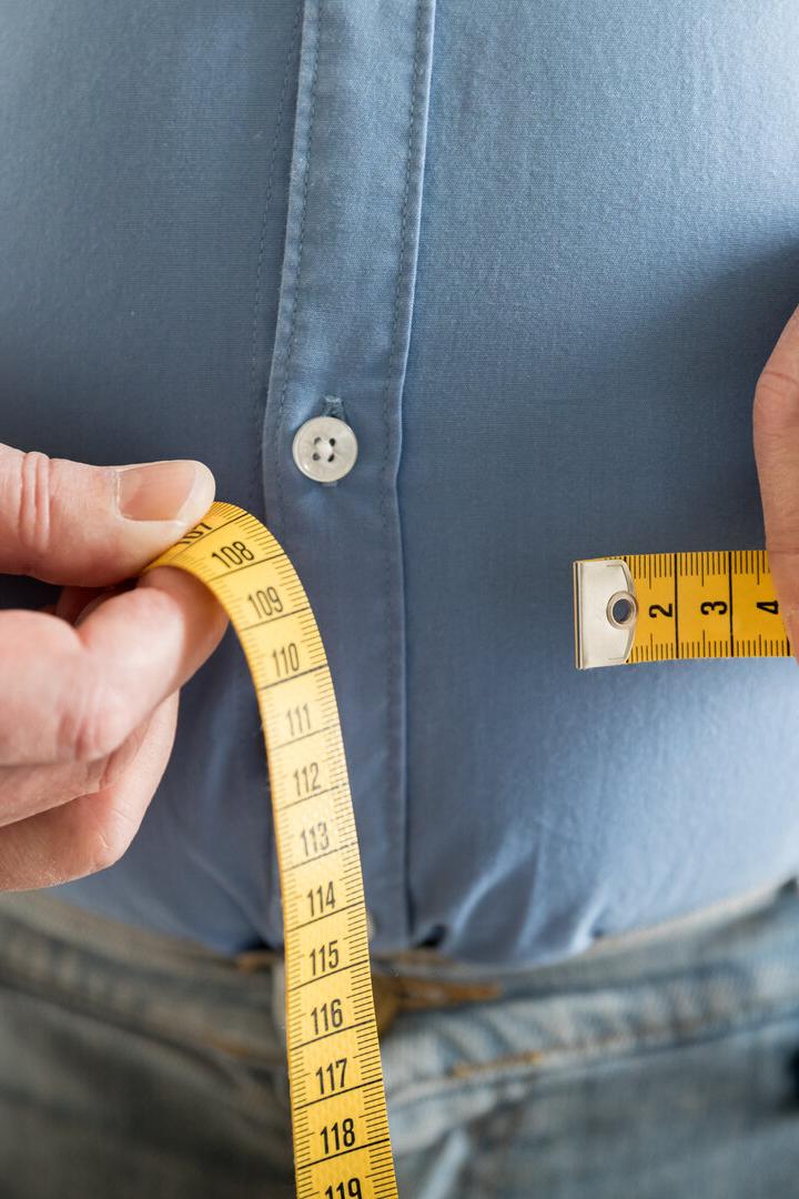 Bauchumfang messen mit einem Maßband bei einer dicken Person.