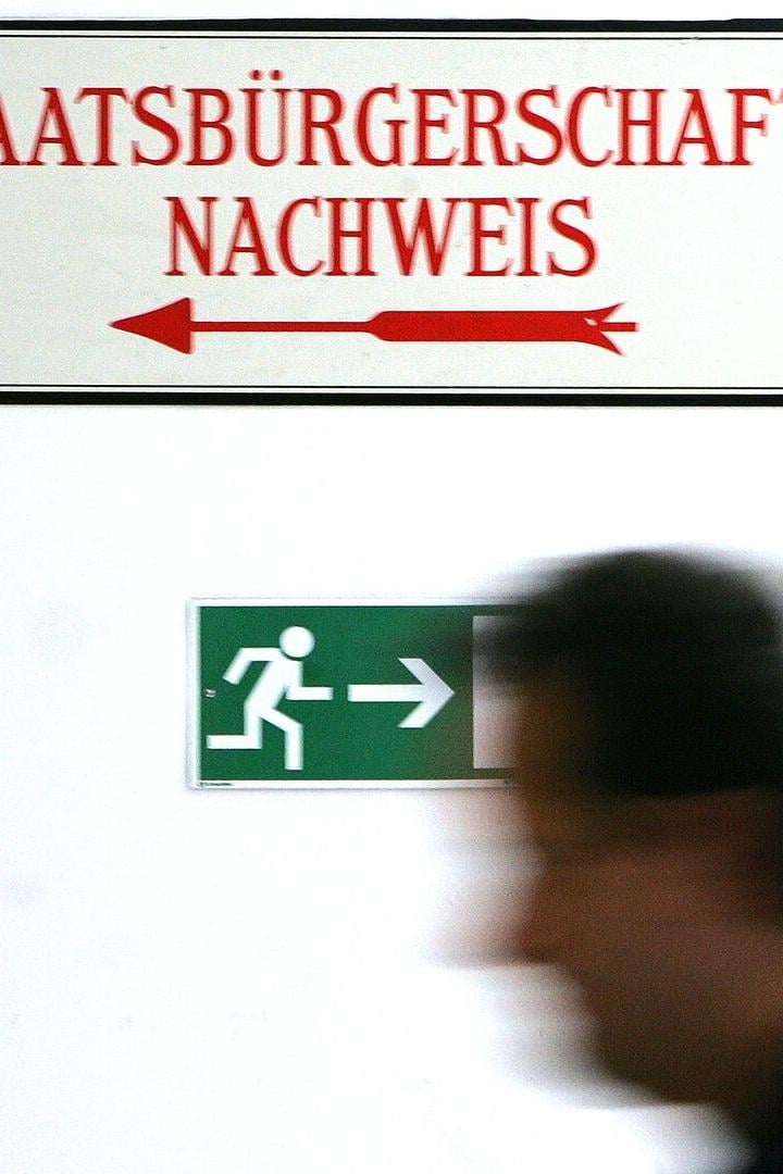 Ein Schild mit der Aufschrift „Staatsbürgerschaftsnachweis“ und ein grünes Notausgangsschild.