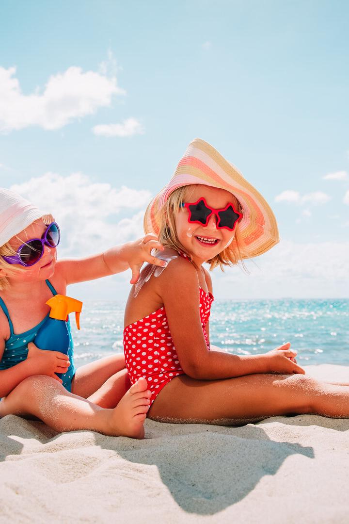 sun protection, cute girls with sun cream at beach
