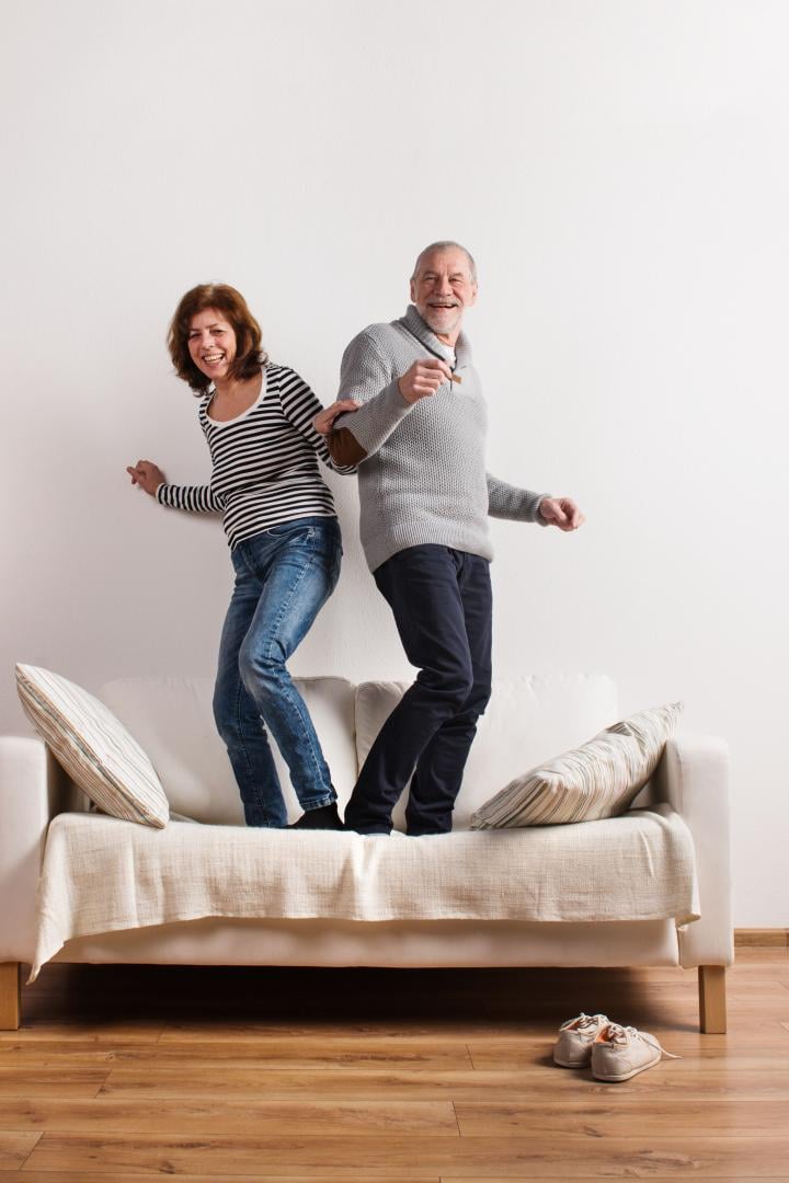 Beautiful senior couple standing on couch, dancing. Studio shot.