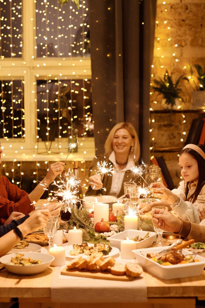 Eine Gruppe von Menschen feiert mit Wunderkerzen an einem festlich gedeckten Tisch.