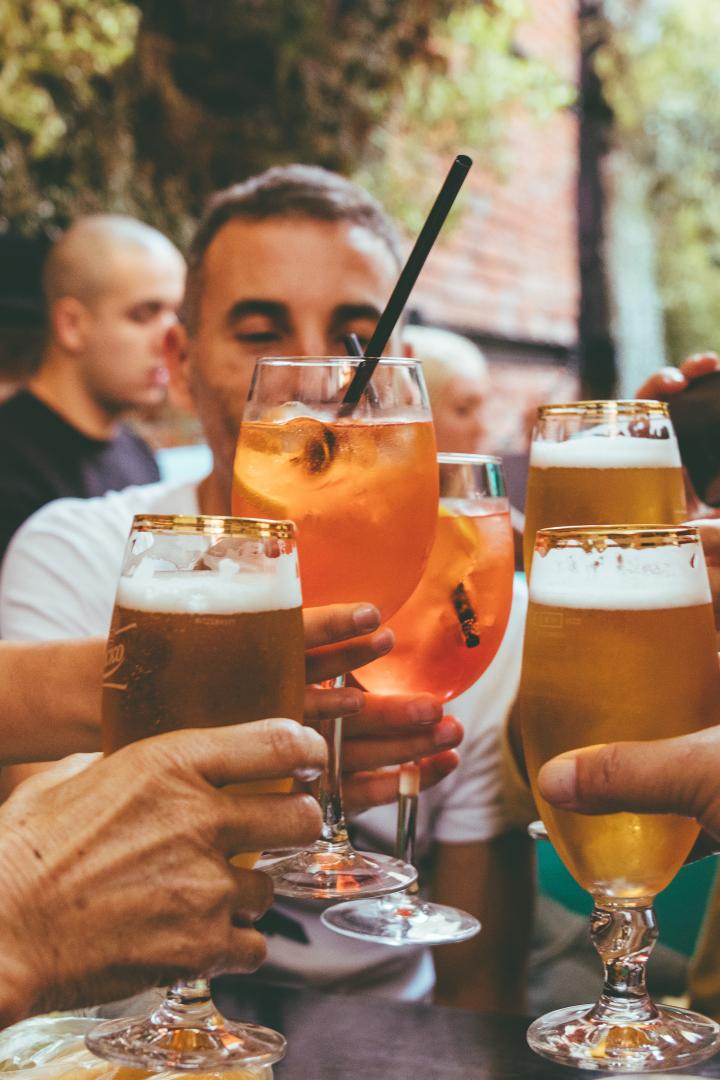 Mehrere Menschen stoßen mit vollen Gläsern an.