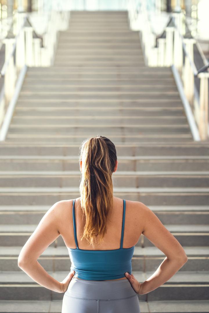 Eine Frau in Sportkleidung steht vor einer langen Treppe.