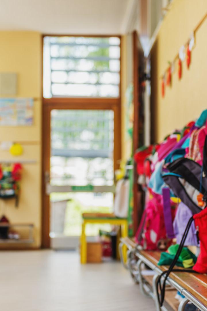Empty hallway in the school, backpacks and bags on hooks, bright recreation room