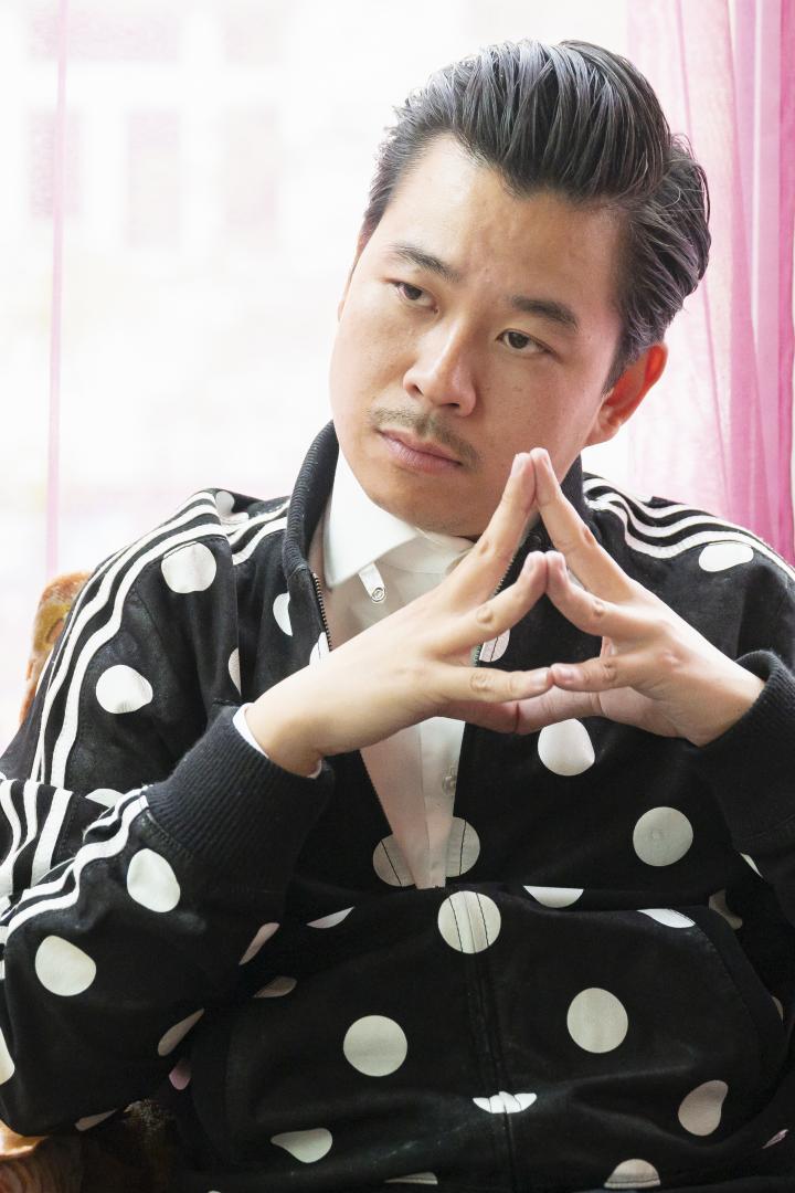 Martin Ho sitzt vor einem Fenster und formt mit seinen Händen eine Pyramide.