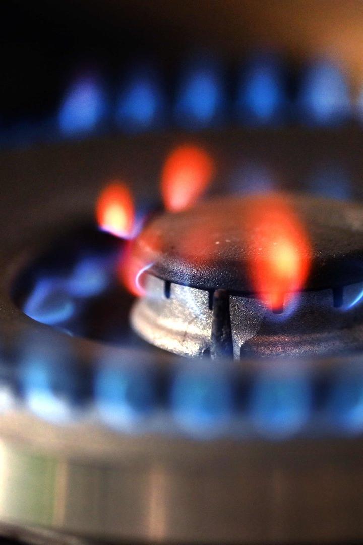 Ein Gasherd brennt mit blauer und orangefarbener Flamme auf einem Metallbrenner.