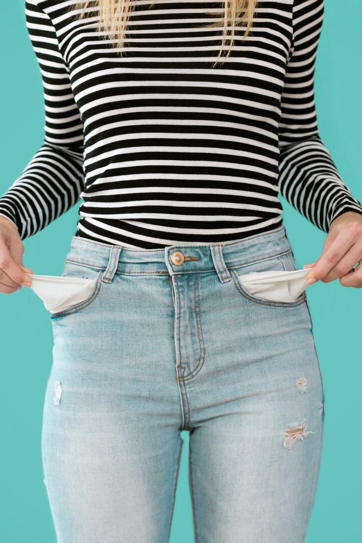 Junge Frau zeigt, dass sie keine finanzielle Reserven in ihren Hosentaschen hat.