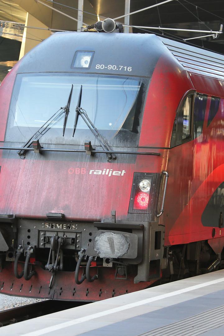 Ein roter ÖBB Railjet-Zug steht am Bahnsteig.