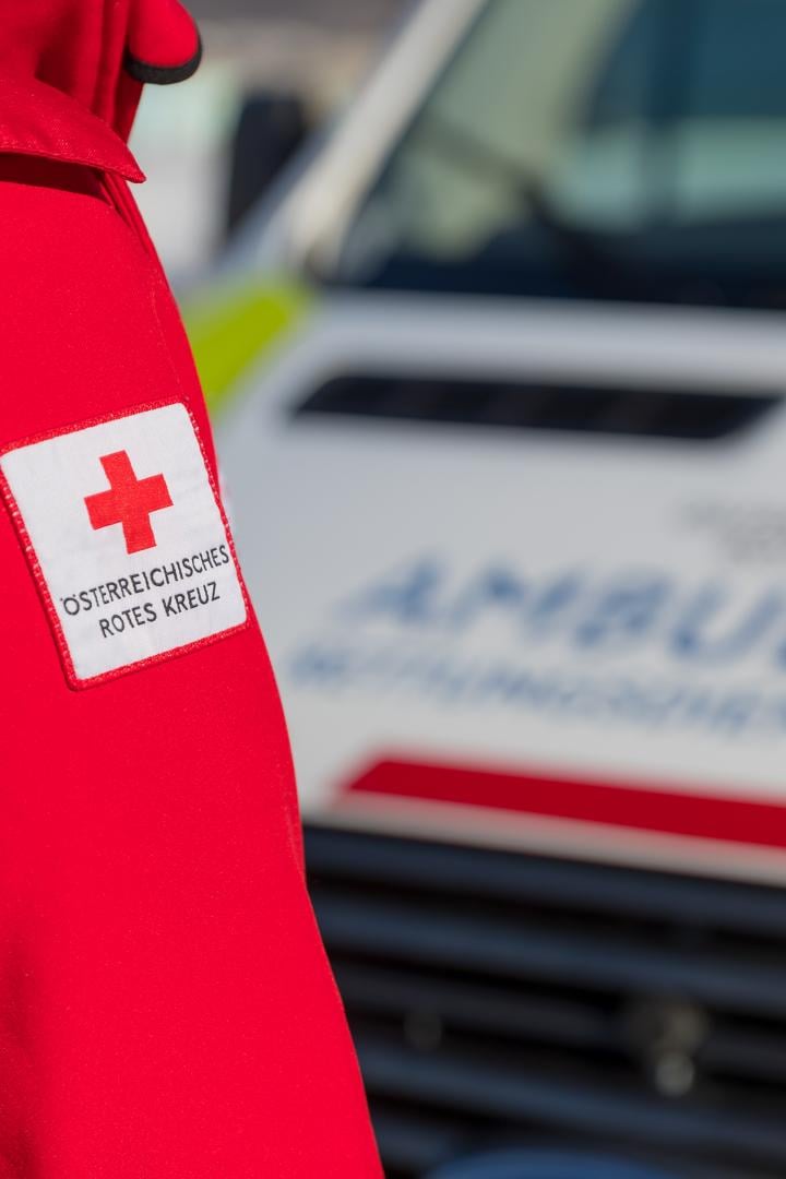 Ein Sanitäter in Rettungsjacke steht vor einem Rettungsfahrzeug.