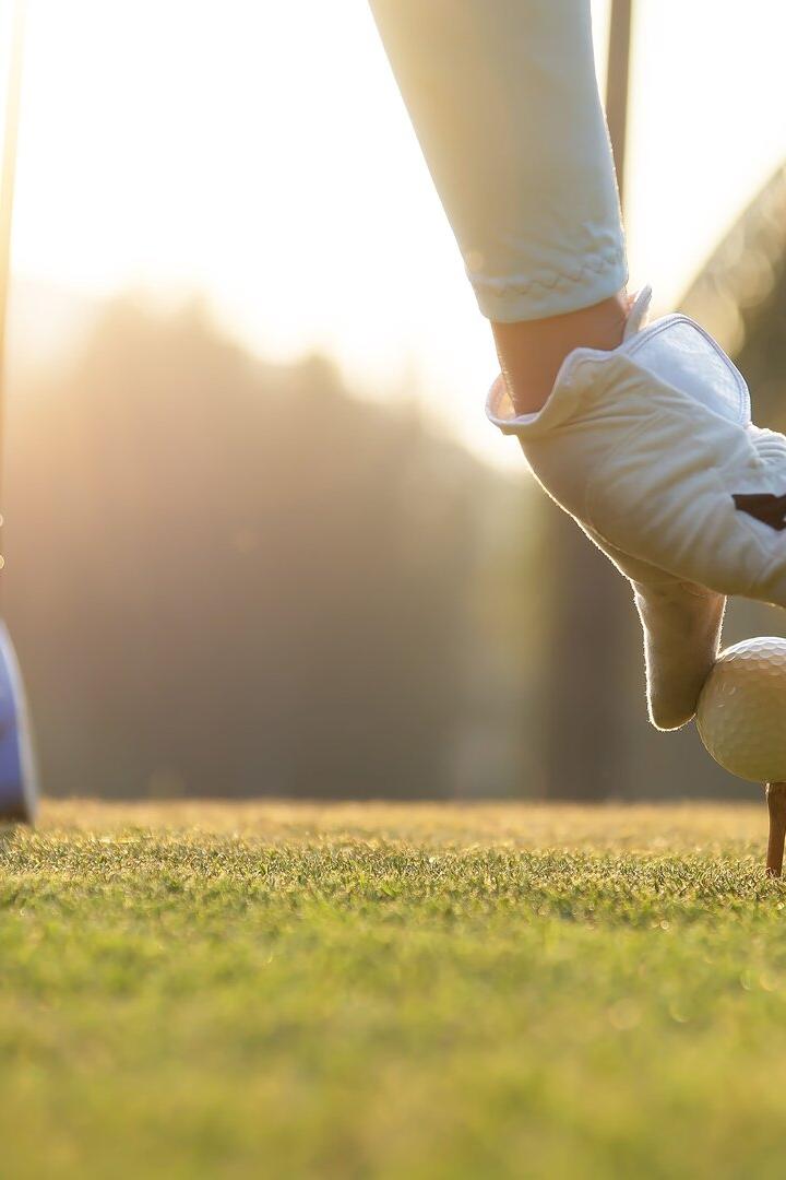 Eine Golferin platziert einen Golfball auf einem Holz-Tee auf dem Abschlag.