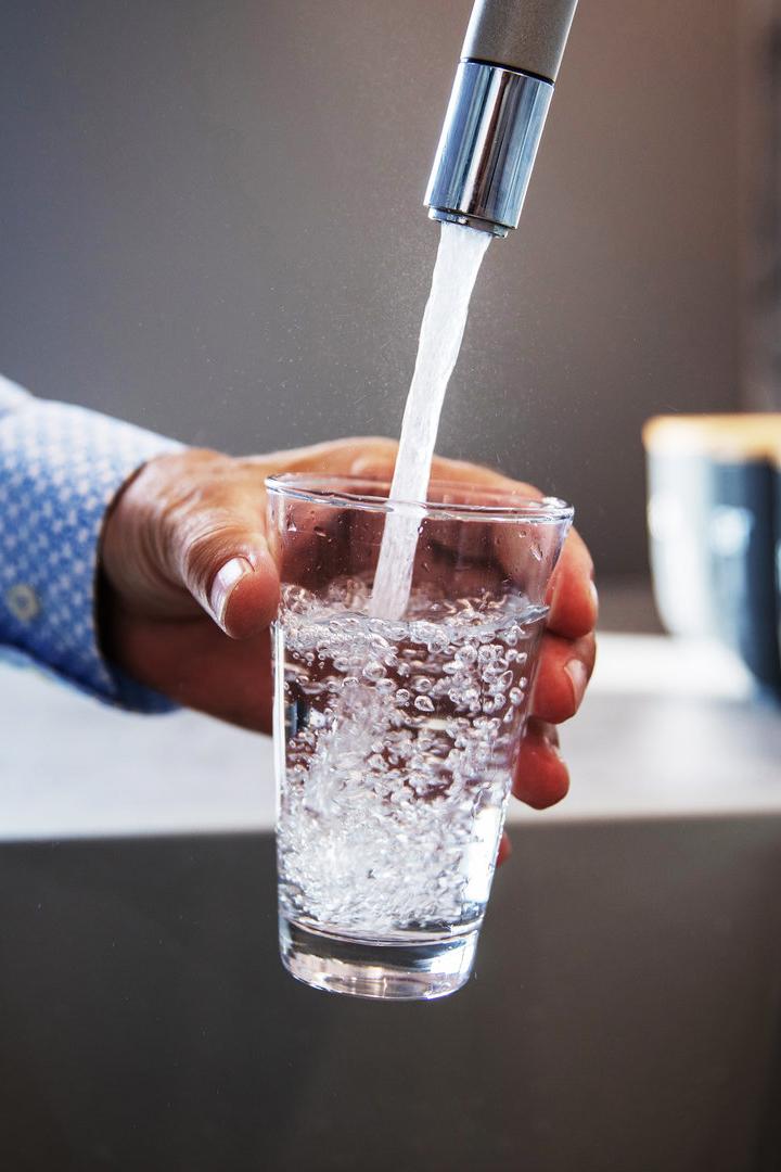 Wasser fließt aus dem Wasserhahn in ein Glas.