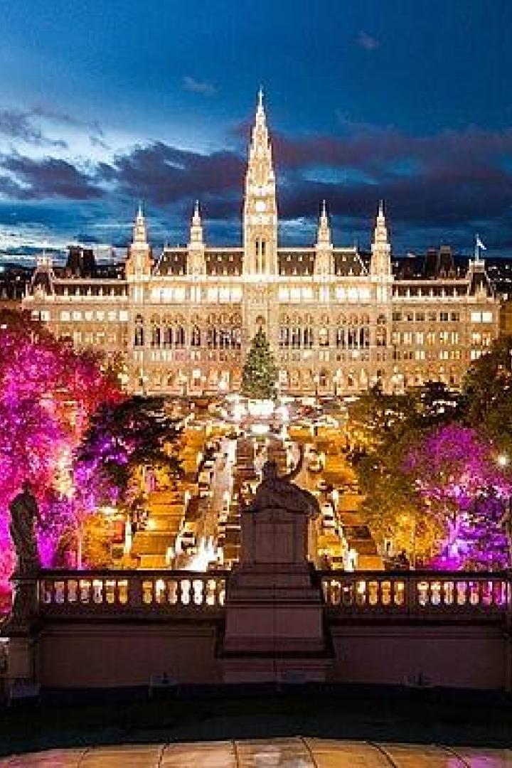 Das Wiener Rathaus und der Rathausplatz sind abends festlich beleuchtet.