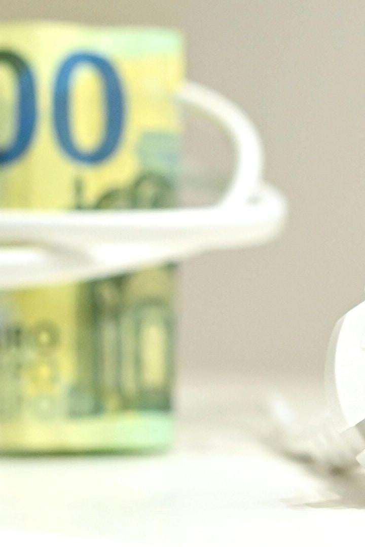 Ein 100-Euro-Schein ist mit einem weißen Stromkabel umwickelt, im Vordergrund ein Stecker.