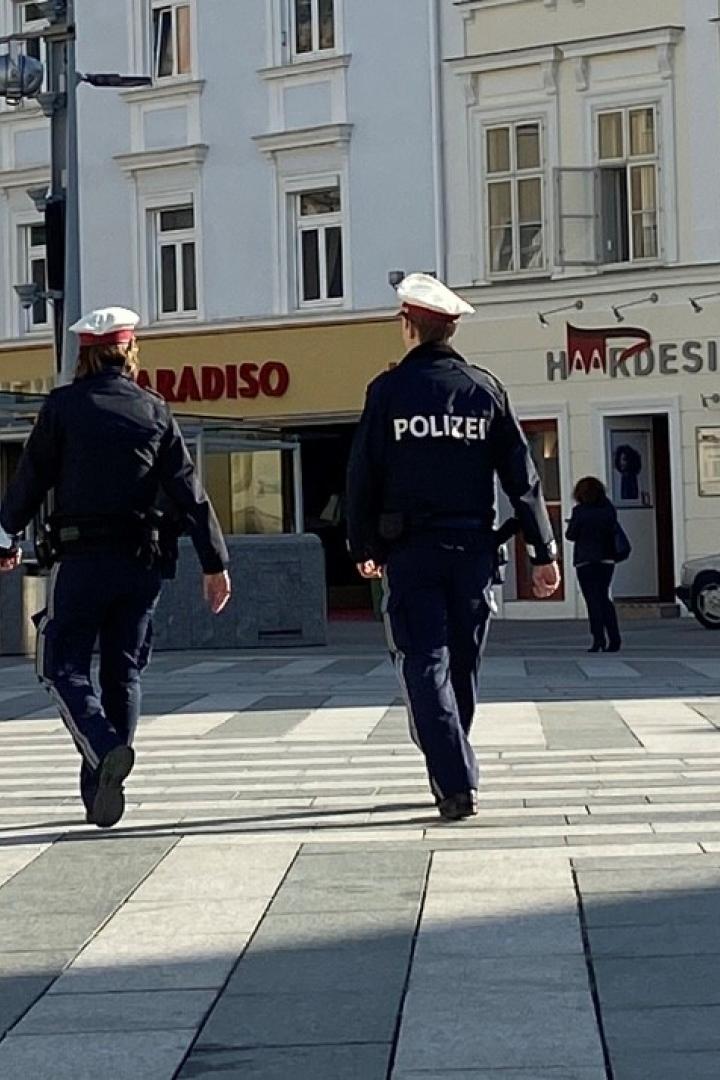 Zwei Polizisten gehen über einen Zebrastreifen in einer Stadt.