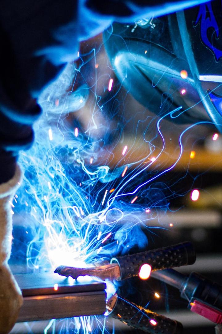 Ein Schweißer arbeitet mit Schutzkleidung an einem Metallrahmen.