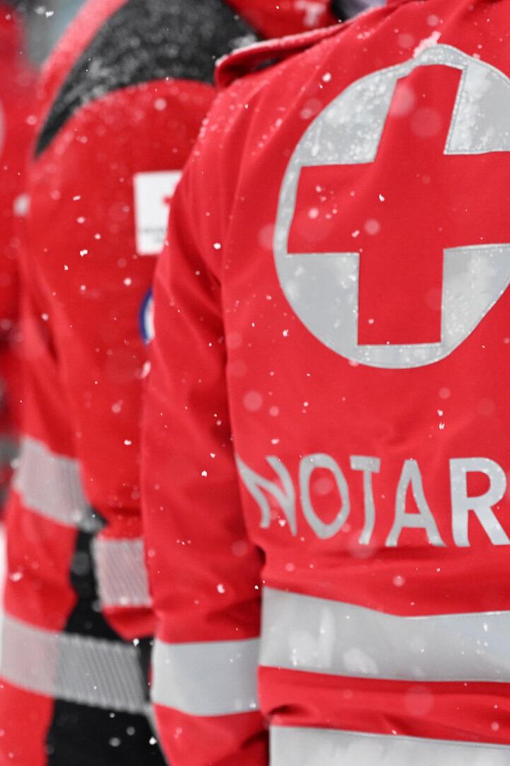 Rote Jacken von Notärzten mit dem Schriftzug "Notarzt" im Schneefall.