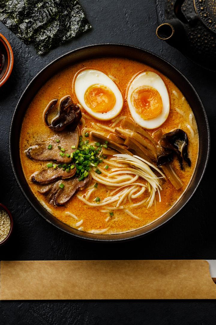 Ramen asian noodle in broth with Beef tongue meat, mushroom and Ajitama pickled egg in bowl on dark background