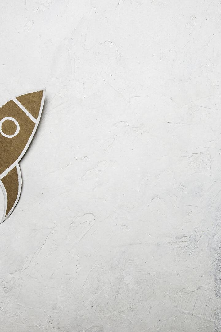 Eine Rakete aus Pappe hebt von zerknülltem Papier auf hellem Untergrund ab.