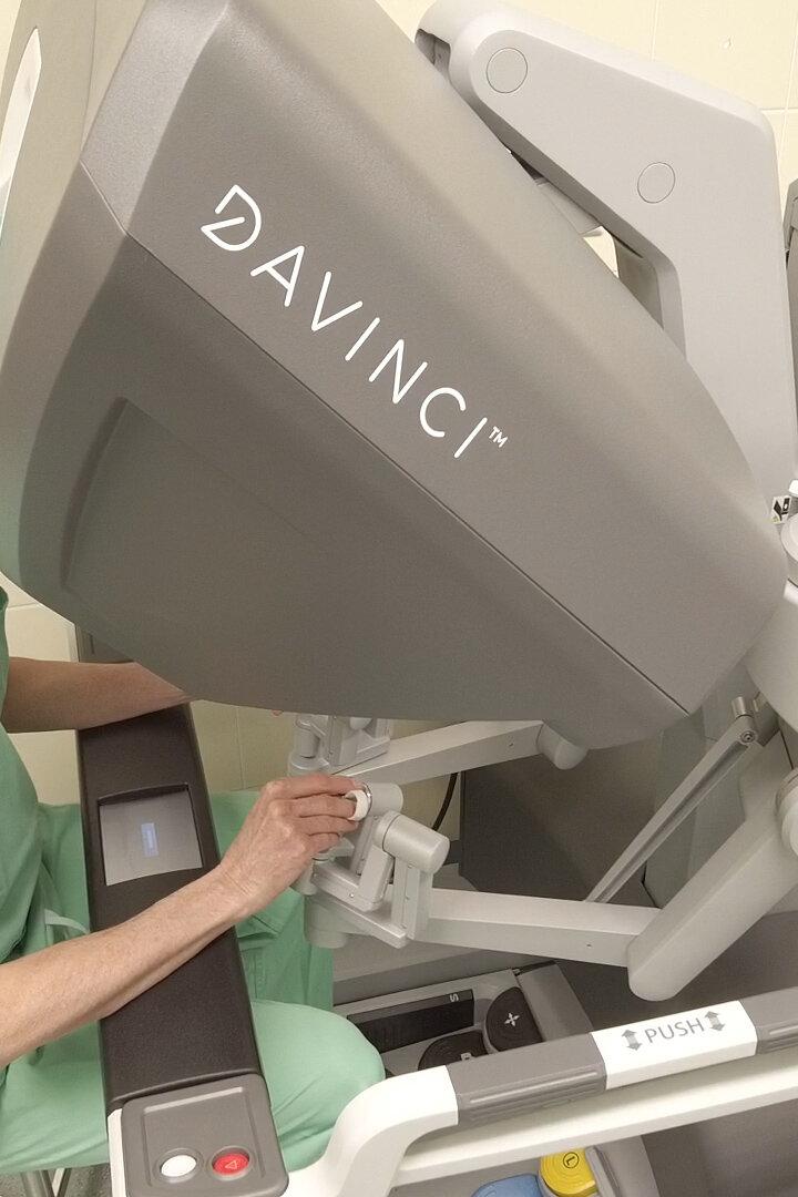 Ein Arzt in grüner OP-Kleidung bedient ein Da Vinci-Robotersystem.