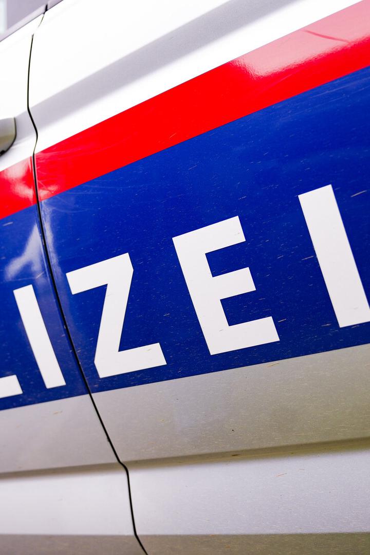 Der Schriftzug „Polizei“ und das österreichische Wappen auf einem Polizeiauto.