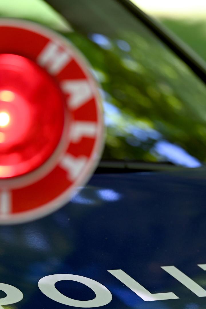 Polizeiauto hinter Kelle mit Aufschrift "Halt Polizei"