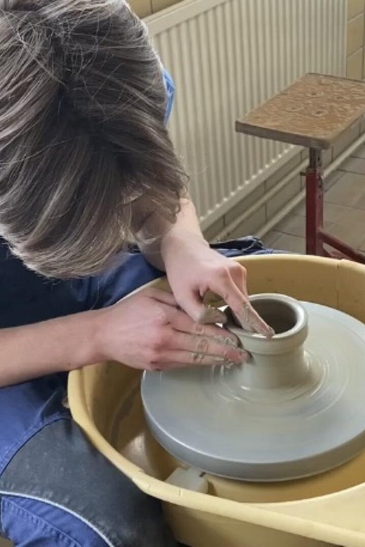 Eine Person formt mit den Händen Ton auf einer Töpferscheibe.