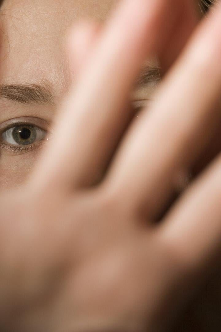 Frau schützt Gesicht mit Händen