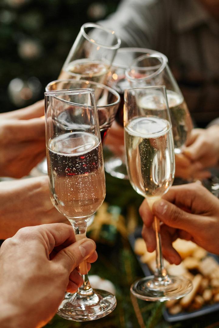 Mehrere Personen stoßen mit Sektgläsern bei einer Weihnachtsfeier an.