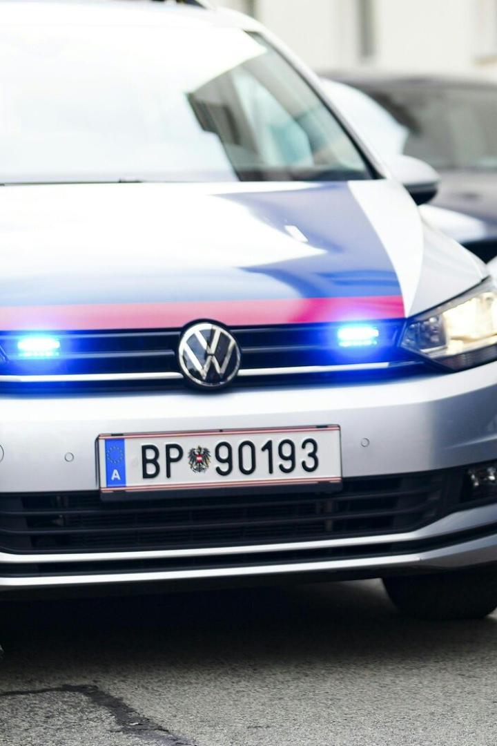 Zwei Polizisten stehen neben einem Streifenwagen.