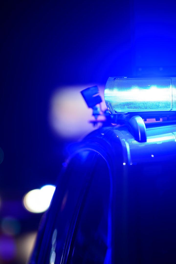 Blaulicht leuchtet auf dem Dach eines Einsatzfahrzeugs in der Dunkelheit.