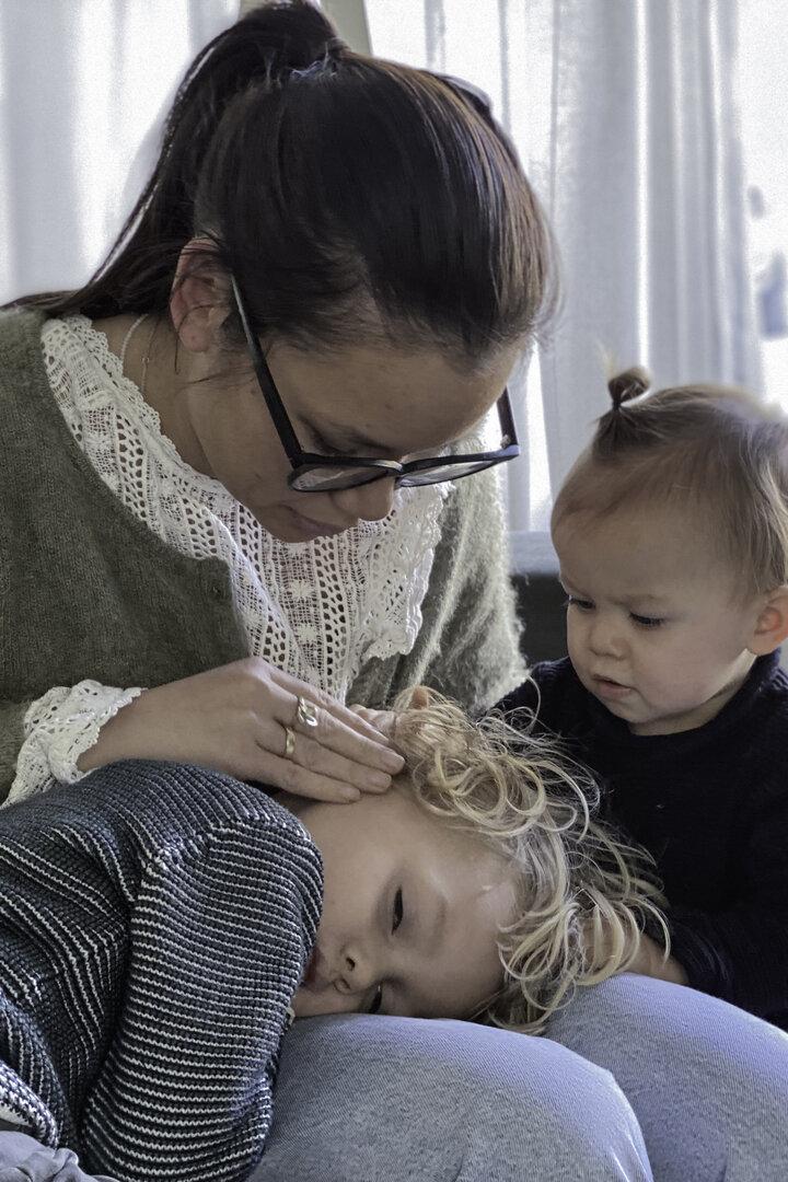 Frau mit Brille tröstet zwei Kinder