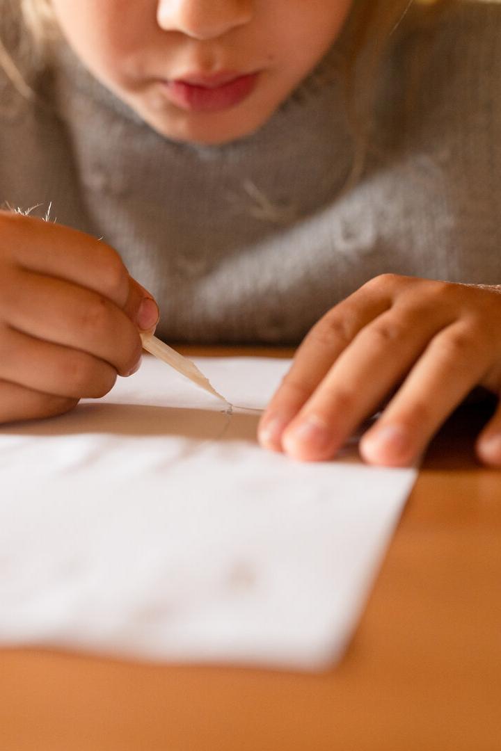 Ein Kind Schreibt auf einem Zettel etwas.
