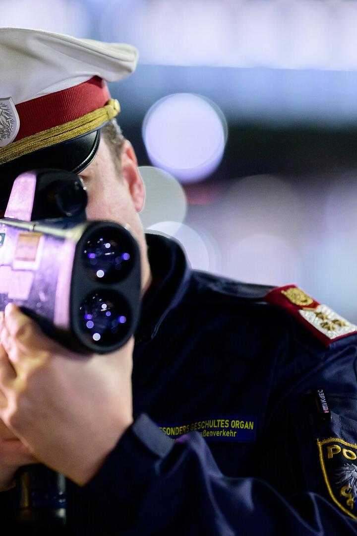 Ein Polizist in Uniform mit Mütze bedient ein Radargerät zur Geschwindigkeitsmessung.