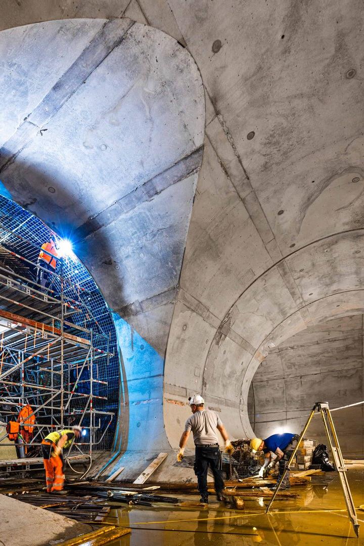 Bauarbeiter arbeiten im Inneren eines großen, im Bau befindlichen Betontunnels.