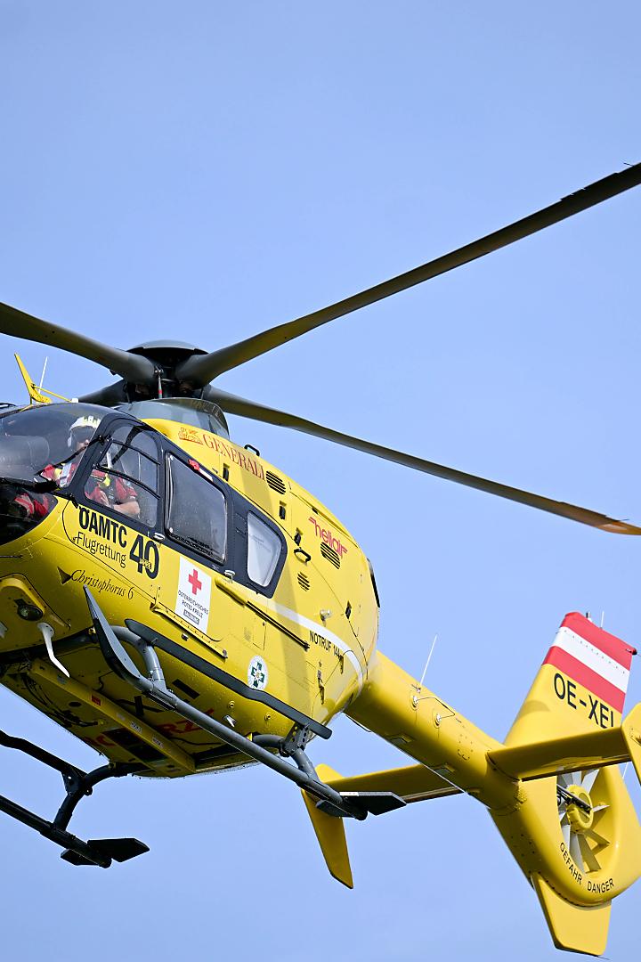 Ein gelber Rettungshubschrauber des ÖAMTC im Flug.