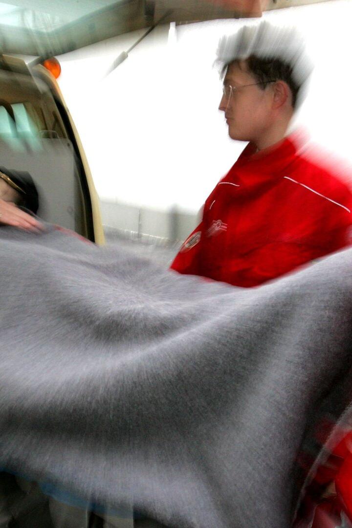 Rettungssanitäter schieben eine Patientin auf einer Trage in einen Krankenwagen.